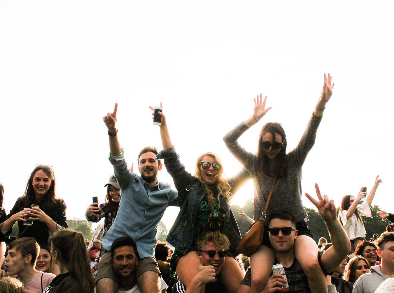 Photo of people sitting on shoulders of other people at a music festival
